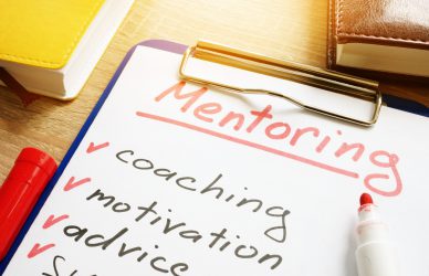 Image of clipboard with a piece of paper clipped to it. Handwritten words Mentoring, coaching, motivation and advice